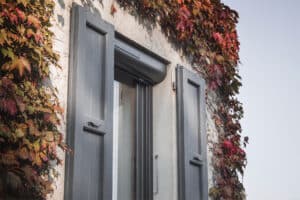 Détail d’une fenêtre rénovée avec volet roulant solaire LAKAL et volets battants gris anthracite