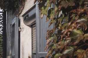 Détail d’une fenêtre rénovée avec volet roulant solaire LAKAL et volets battants gris anthracite