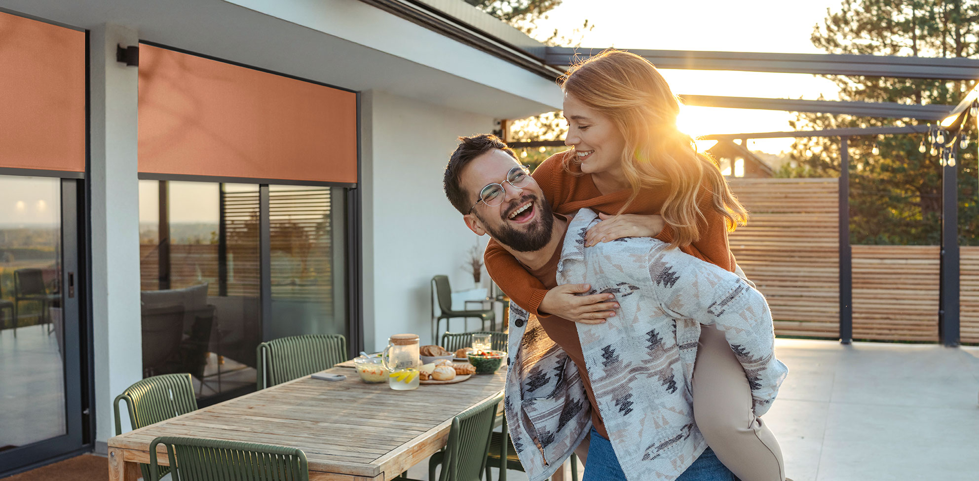 Junges Paar auf Terrasse im Hintergrund ist ein Fenster mit Screen zu sehen
